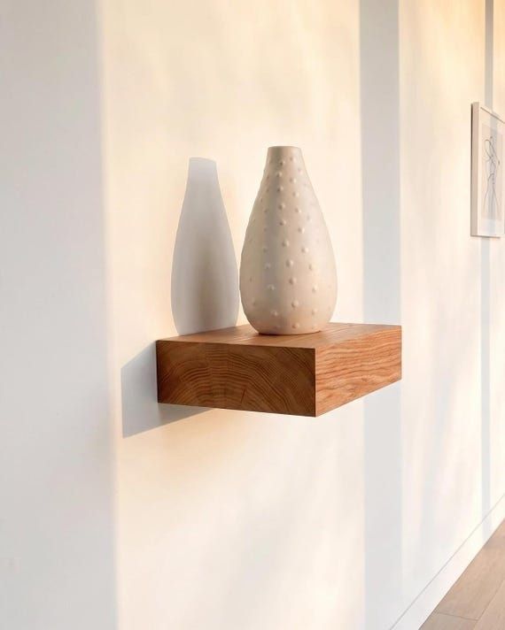 Twee keramische vazen op een warme houten wandplank
